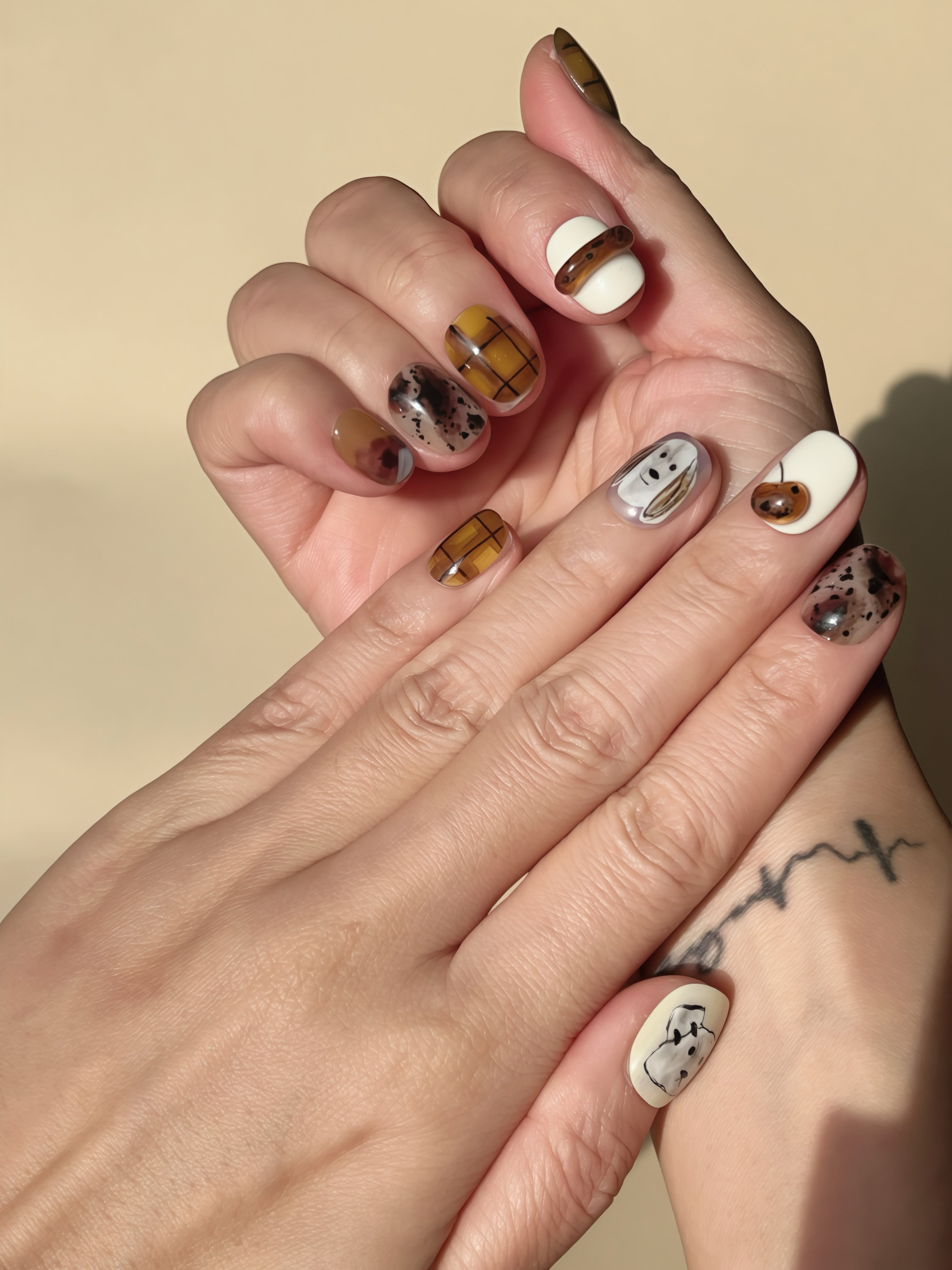 Close-up of Sketchy Puppy press-on nails with caramel tones, plaid stripes, and cute puppy art