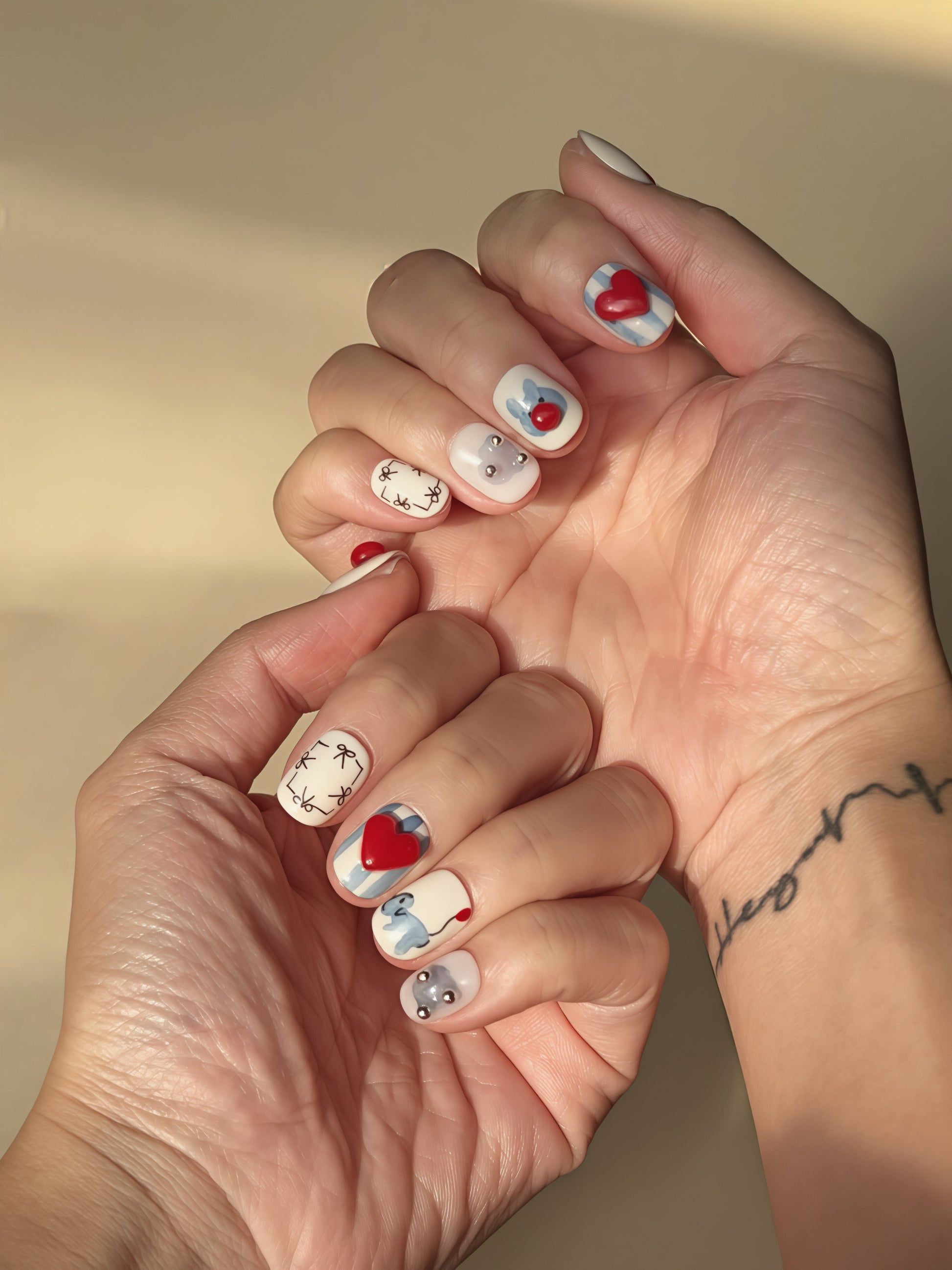 Cute red and blue press-on nails featuring puppies, hearts, bows, and silver studs