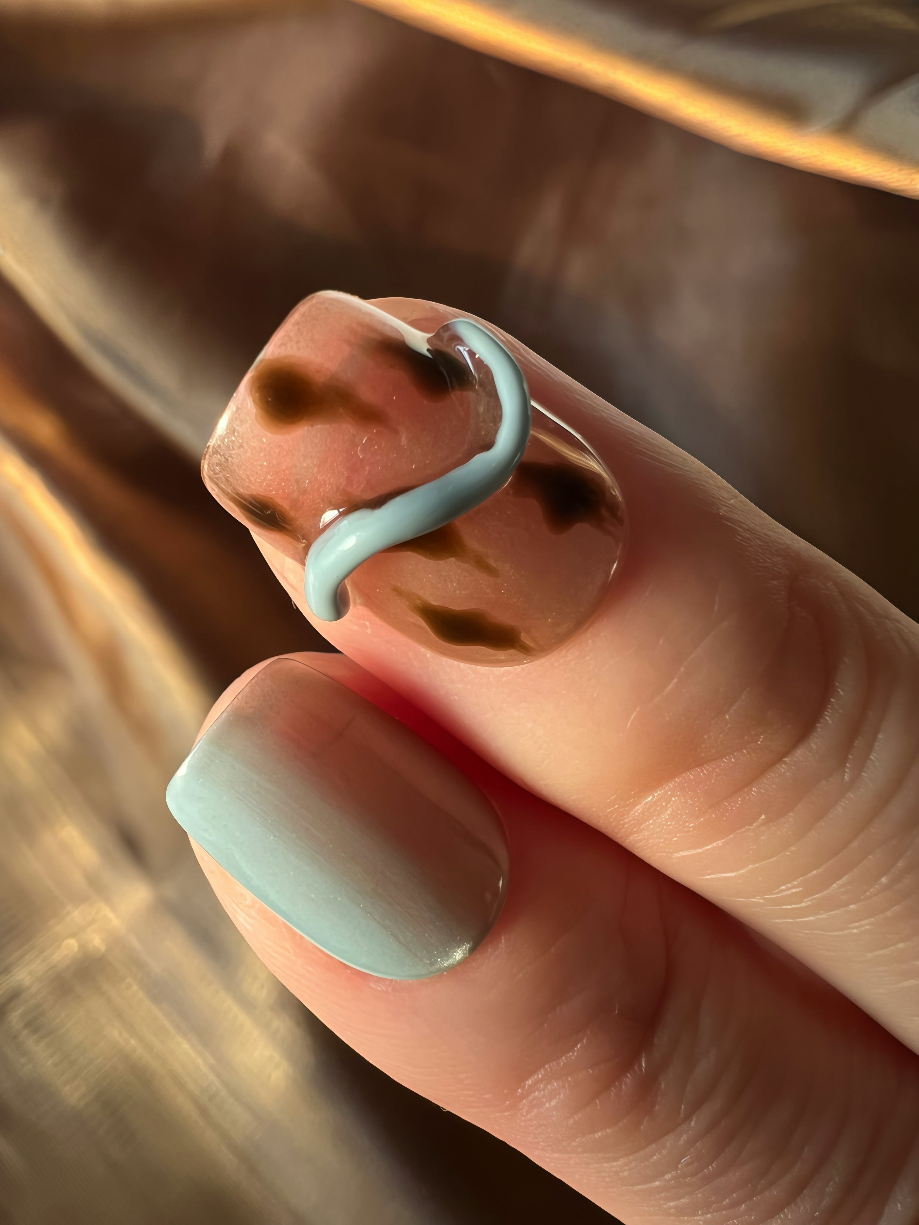 Close-up of brown and blue 3D wavy press on nails in warm natural light, textured stick on nails UK
