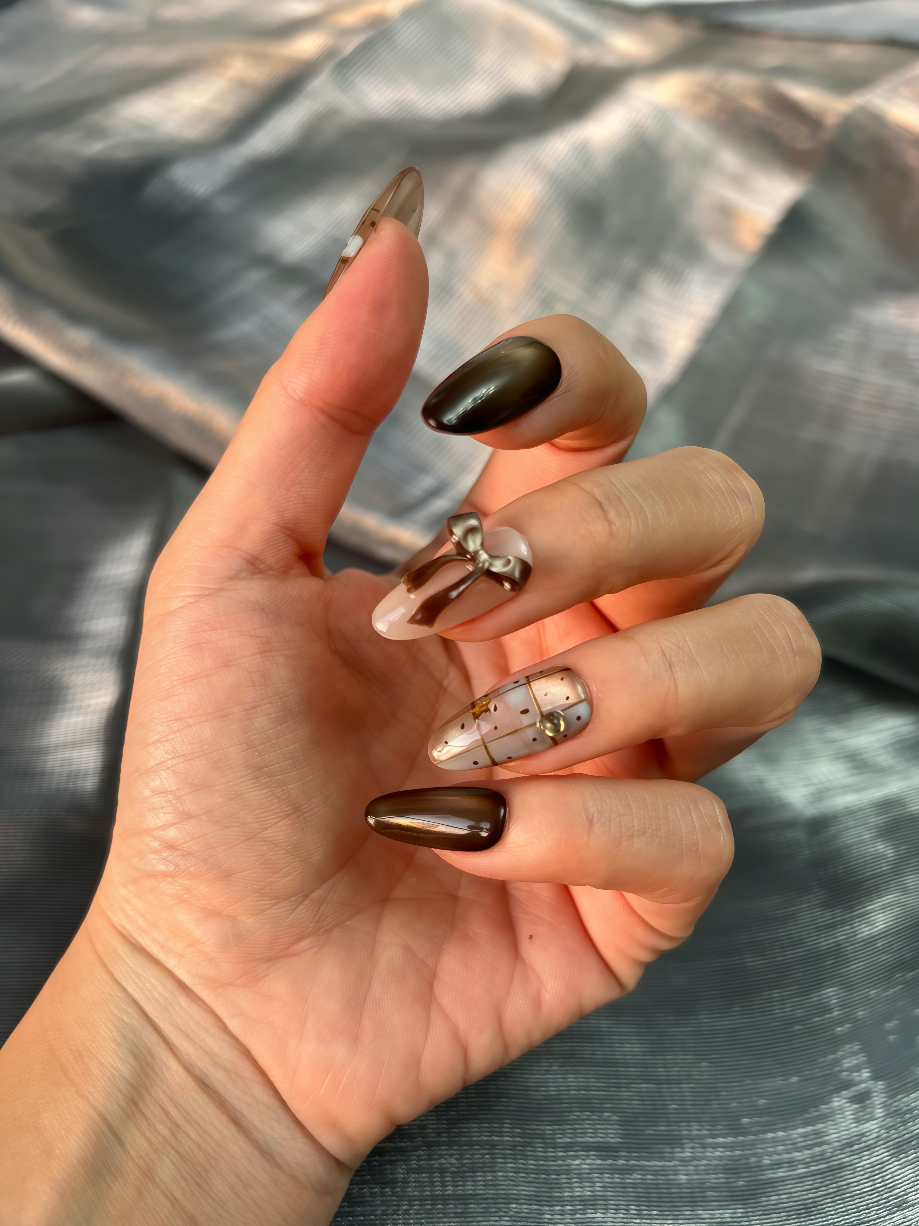 Cocoa Giftbox brown winter press-on nails with cat-eye gradient, gold giftbox accents and 3D bow — elegant festive manicure shown on hand for UK and Europe.