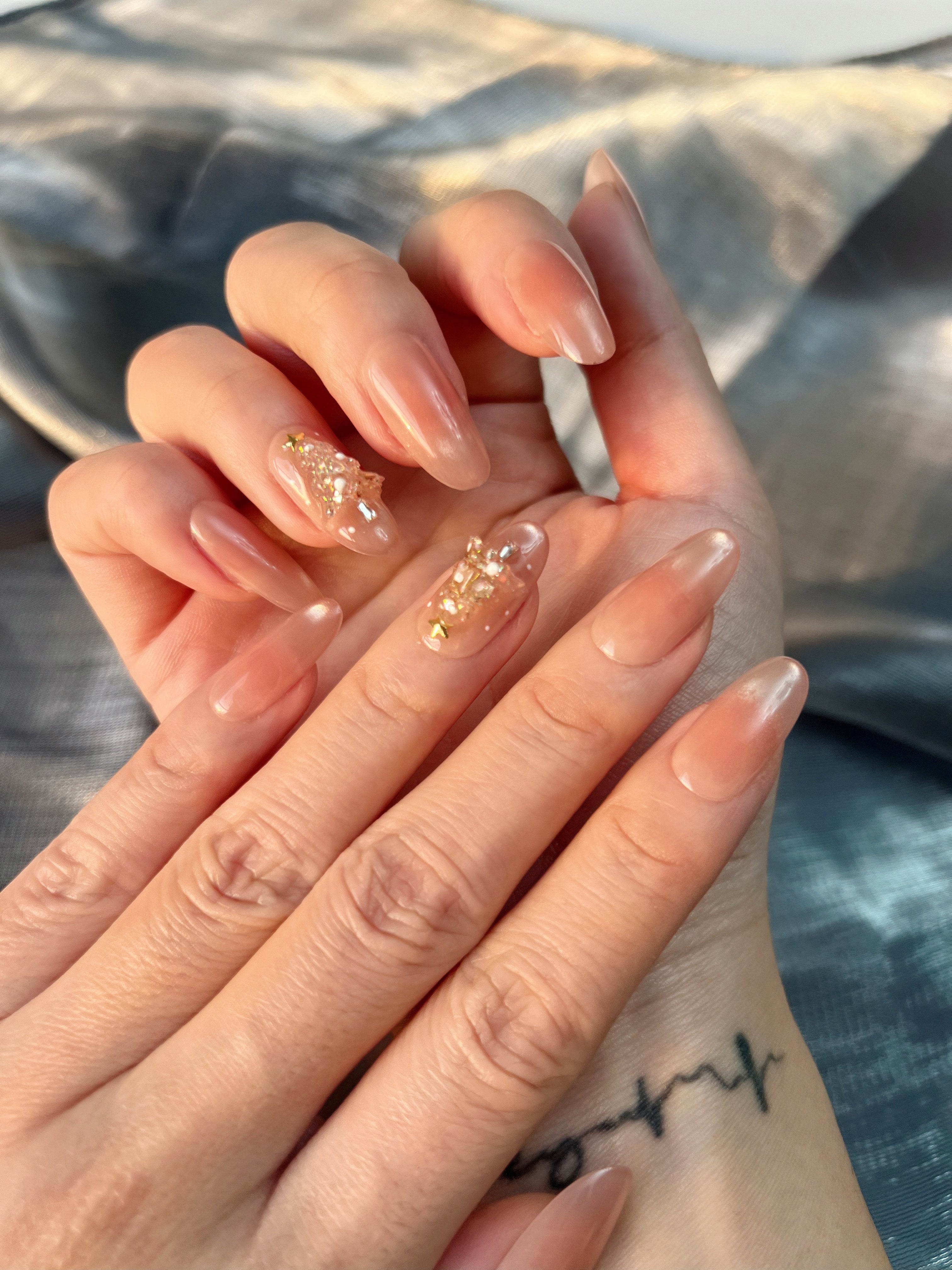 Golden Fir nude-gold press-on nails with a handcrafted 3D Christmas tree made from gems and micro-pearls, shown on hand under soft winter light.