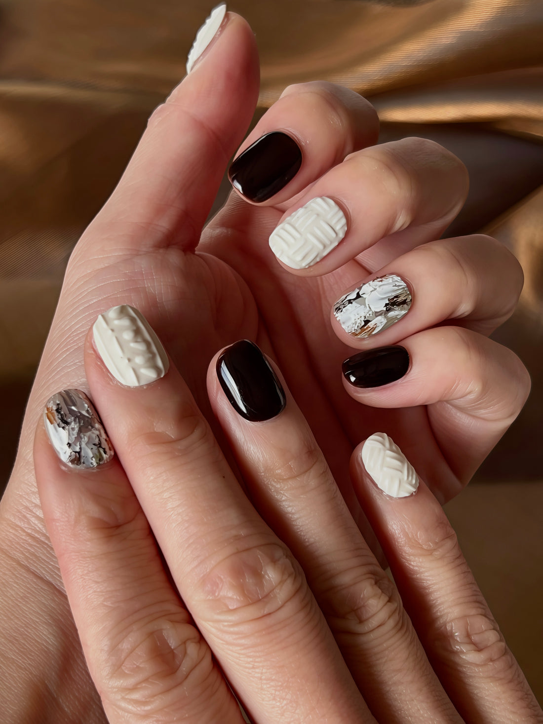 Knitted Chestnuts press-on nails featuring knitted textures, chestnut brown tones, glossy black and metallic marbled accents for a warm winter manicure.