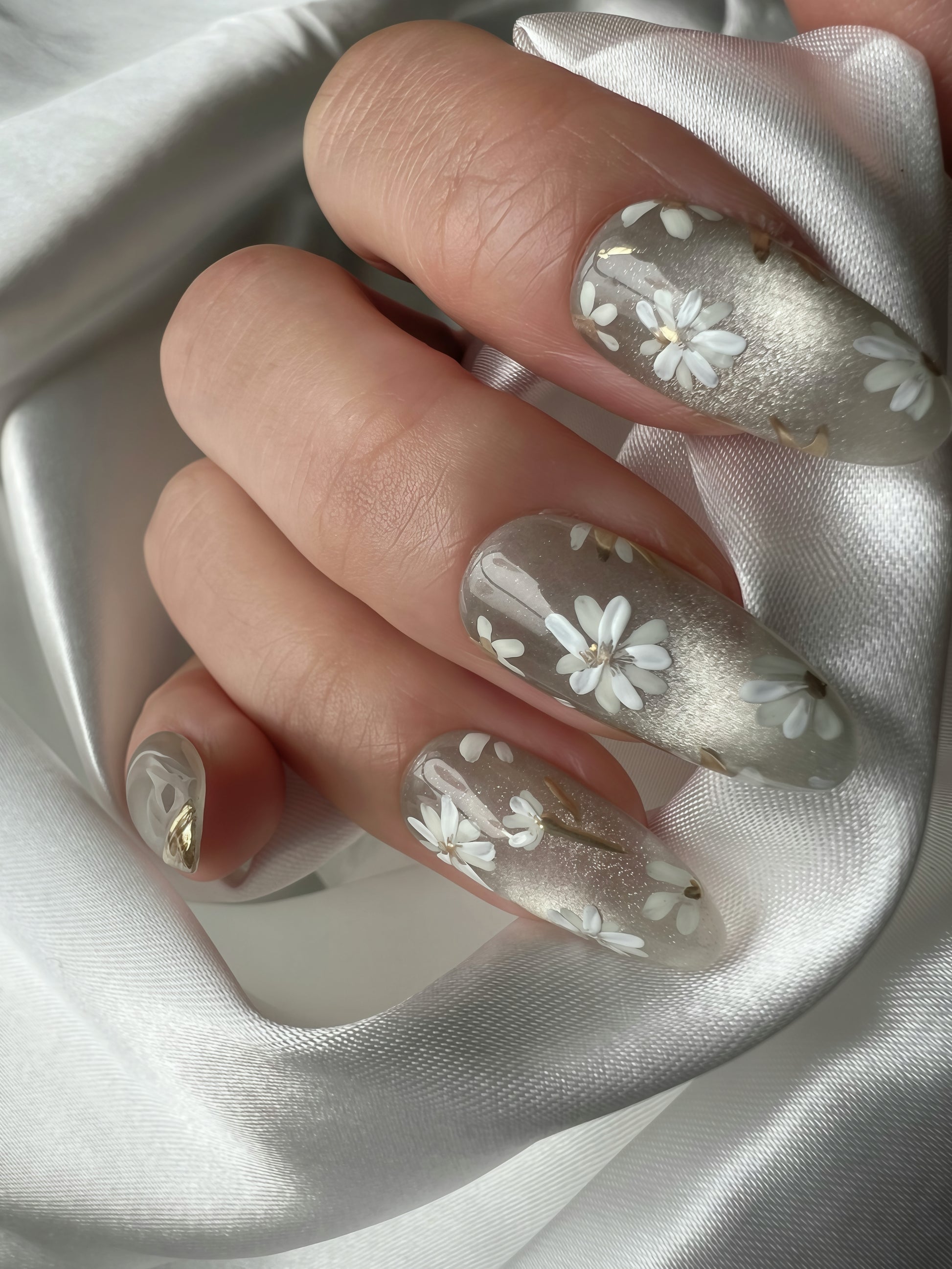 Hand wearing Jade Whisper jade grey press-on nails with hand-painted white flowers and gold accents