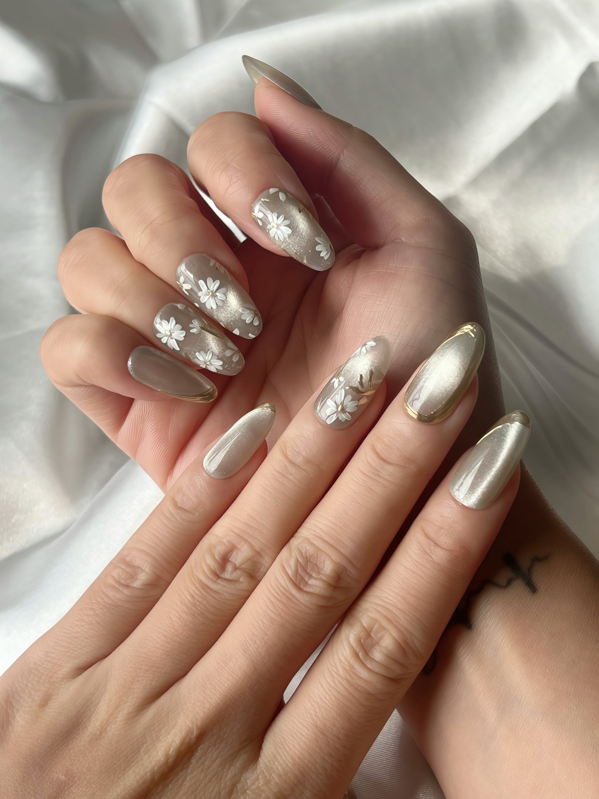 Close-up of Jade Whisper floral jade grey press-on nails styled on hand under soft satin light