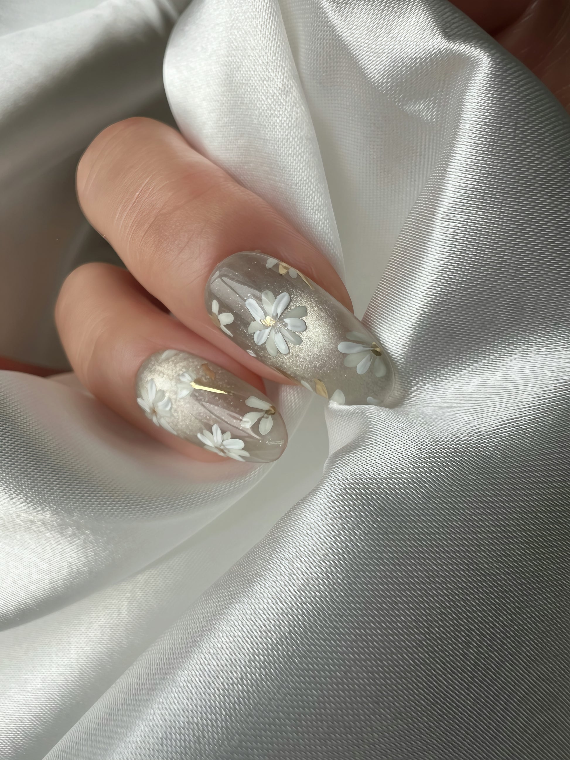 Close-up of Jade Whisper floral jade grey press-on nails styled on hand under soft satin light