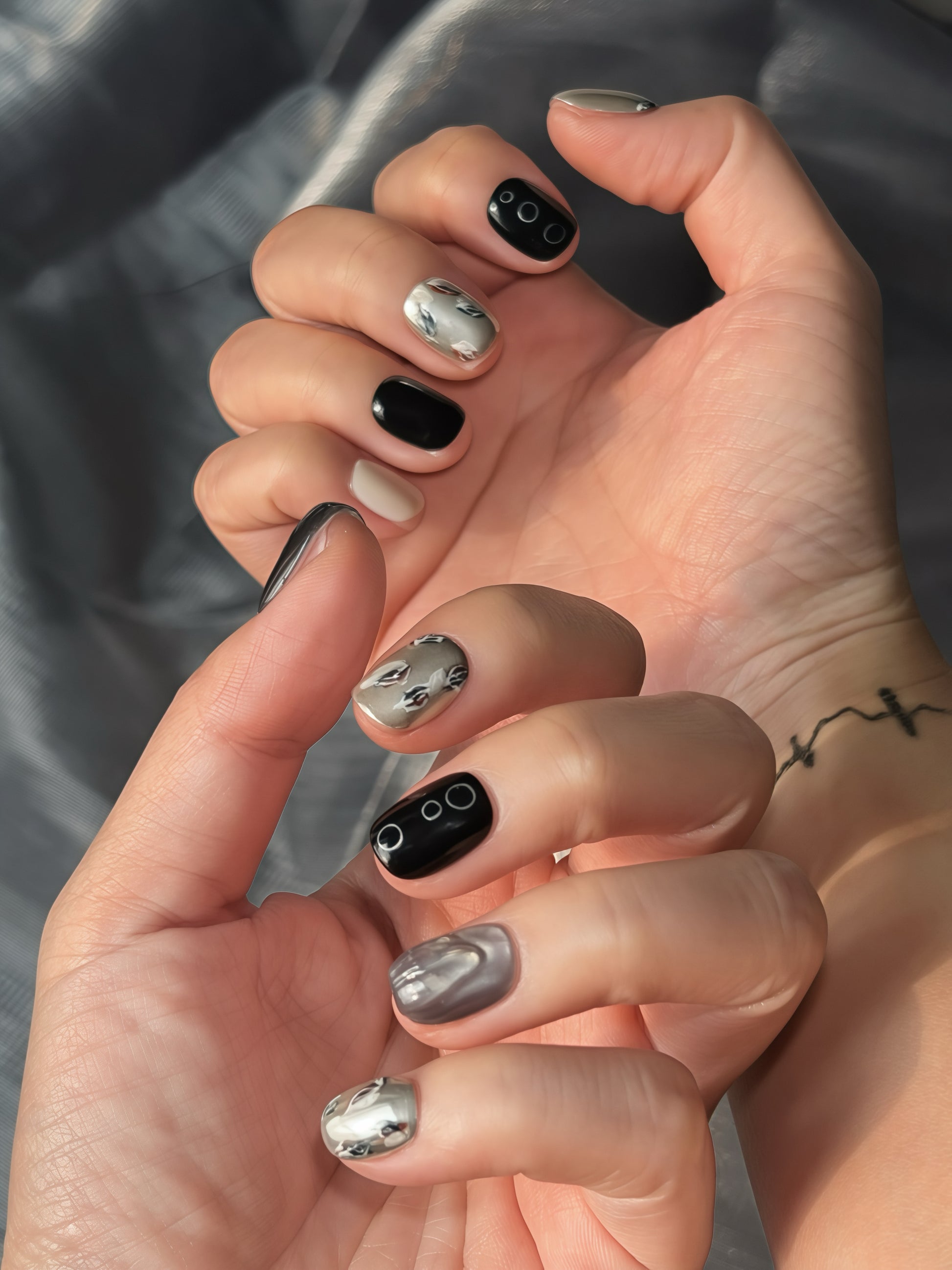 Silent Peaks black and silver press-on nails with chrome and leaf details under natural light