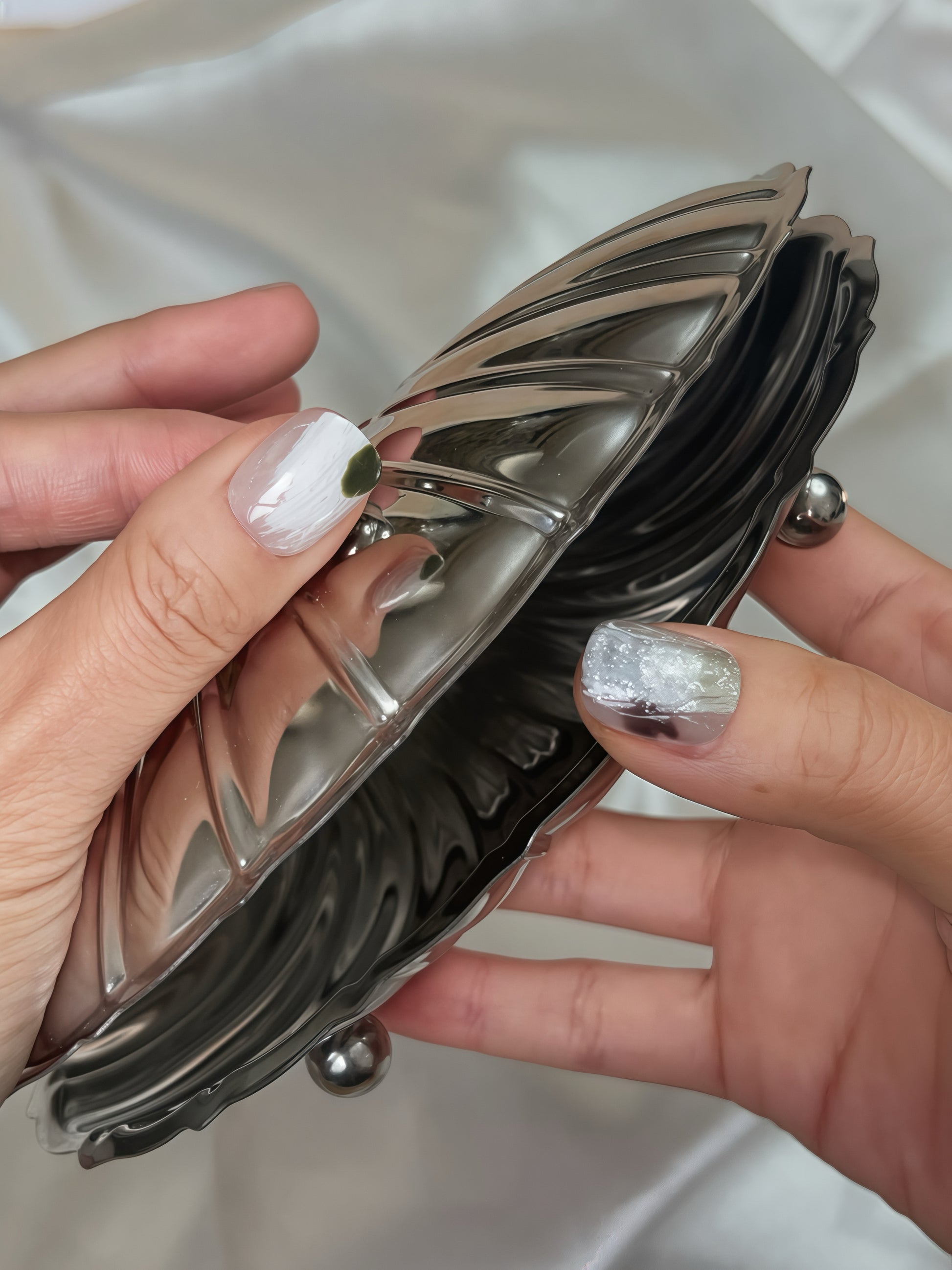 Close-up of Moss Whisper press-on nails — white and silver textured nail art with moss-green accent, hand-painted reusable press-on nails by Momento.