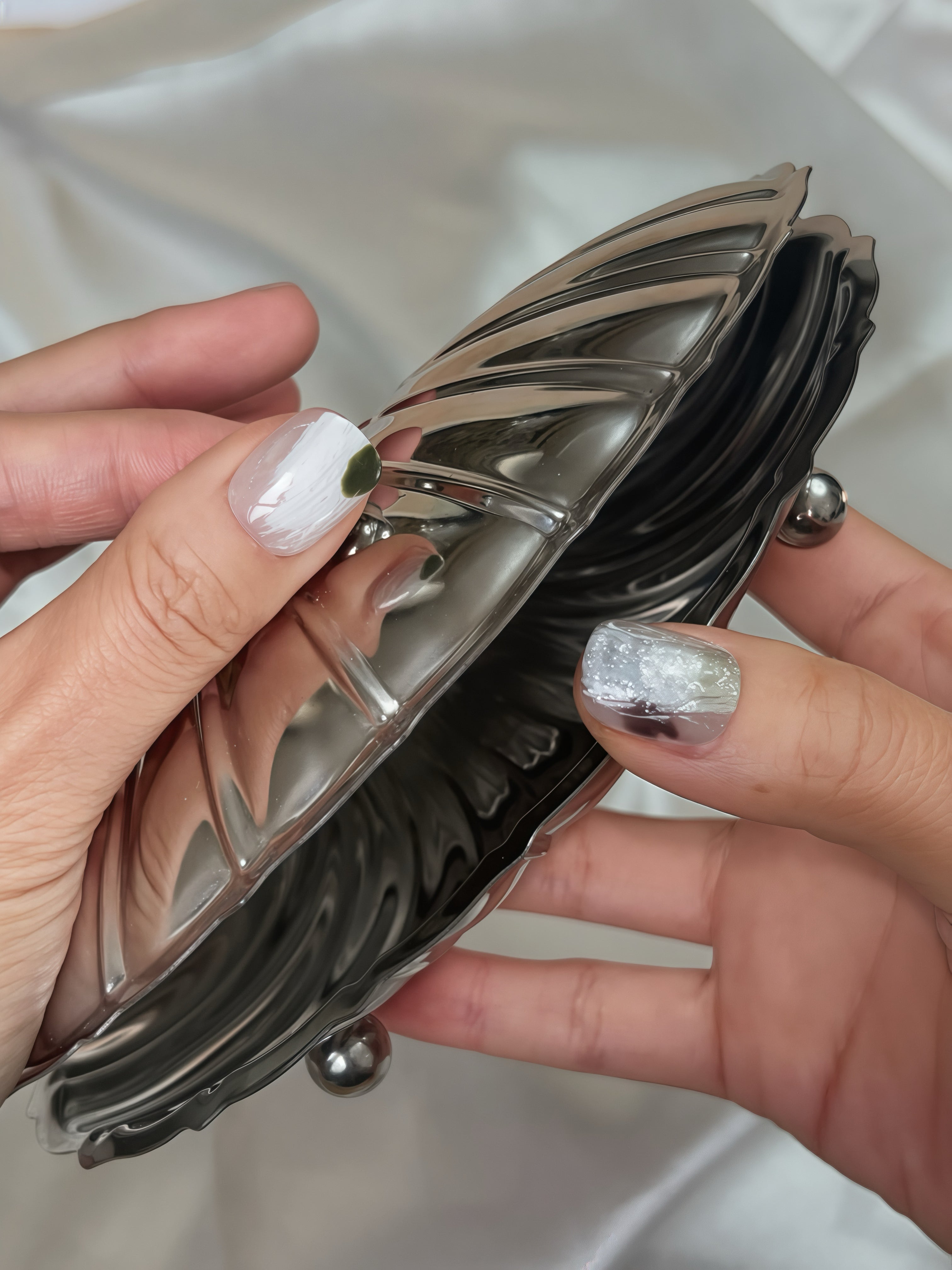 Close-up of Moss Whisper press-on nails — white and silver textured nail art with moss-green accent, hand-painted reusable press-on nails by Momento.