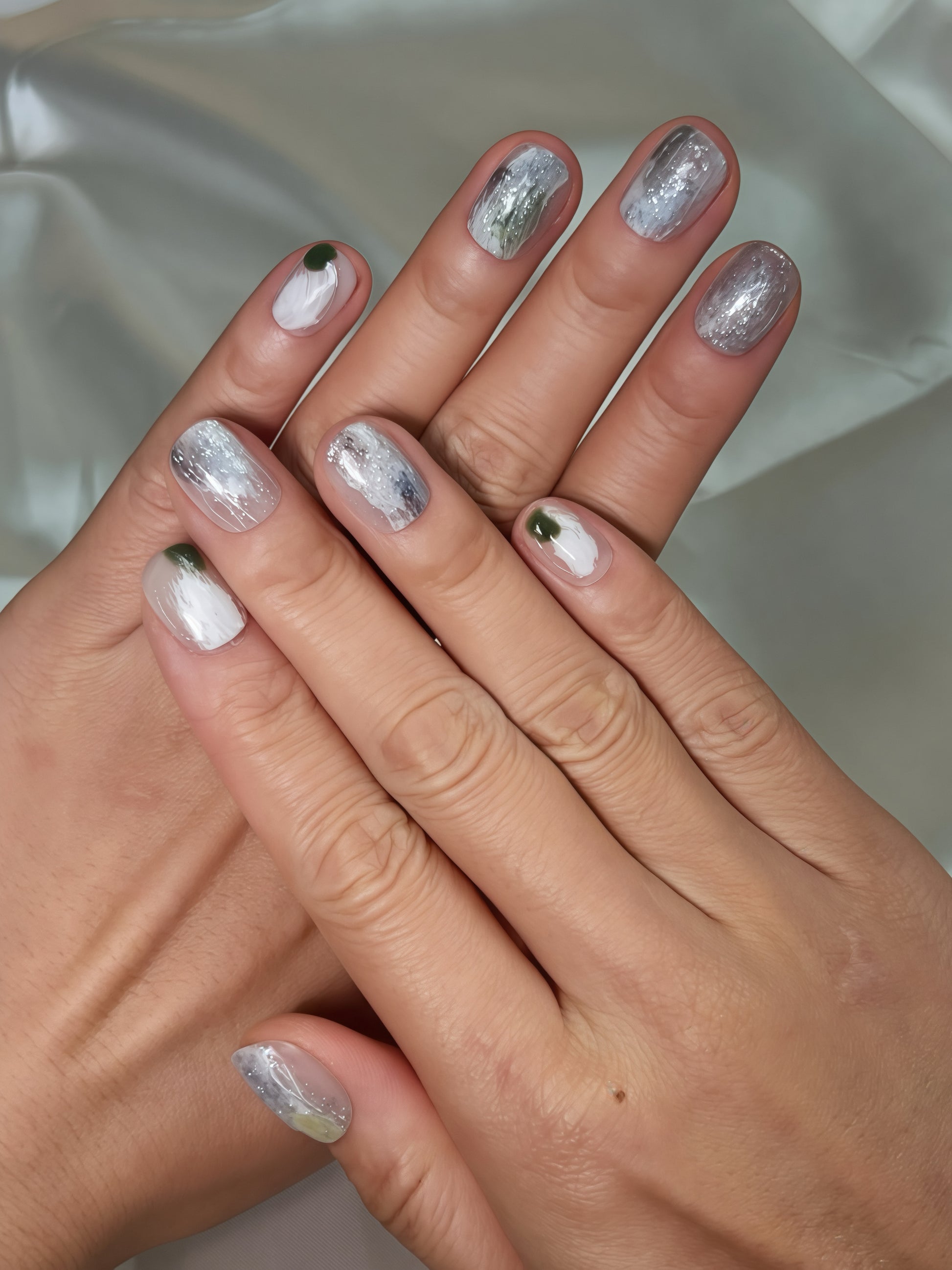 Moss Whisper press-on nails shown on hands — silver-white textured nails with subtle moss-green detail, reusable salon-quality press-on nails for everyday wear.