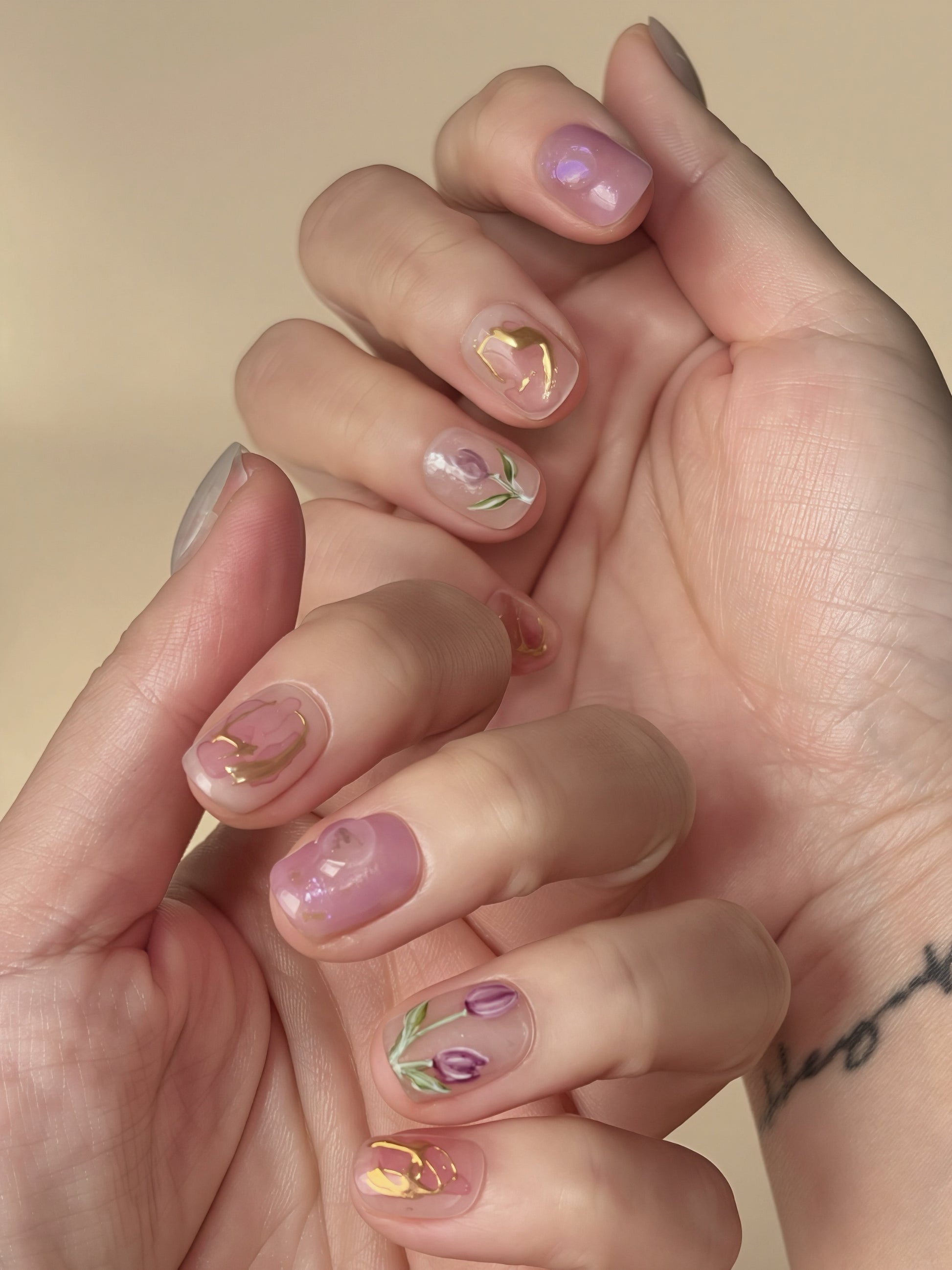 Floral press-on nails in pink and purple tones from the Tulip Reverie set, shown on hands