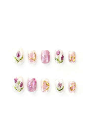 Flatlay of Tulip Reverie press-on nails with pink and purple tulip floral designs and pearlescent accents